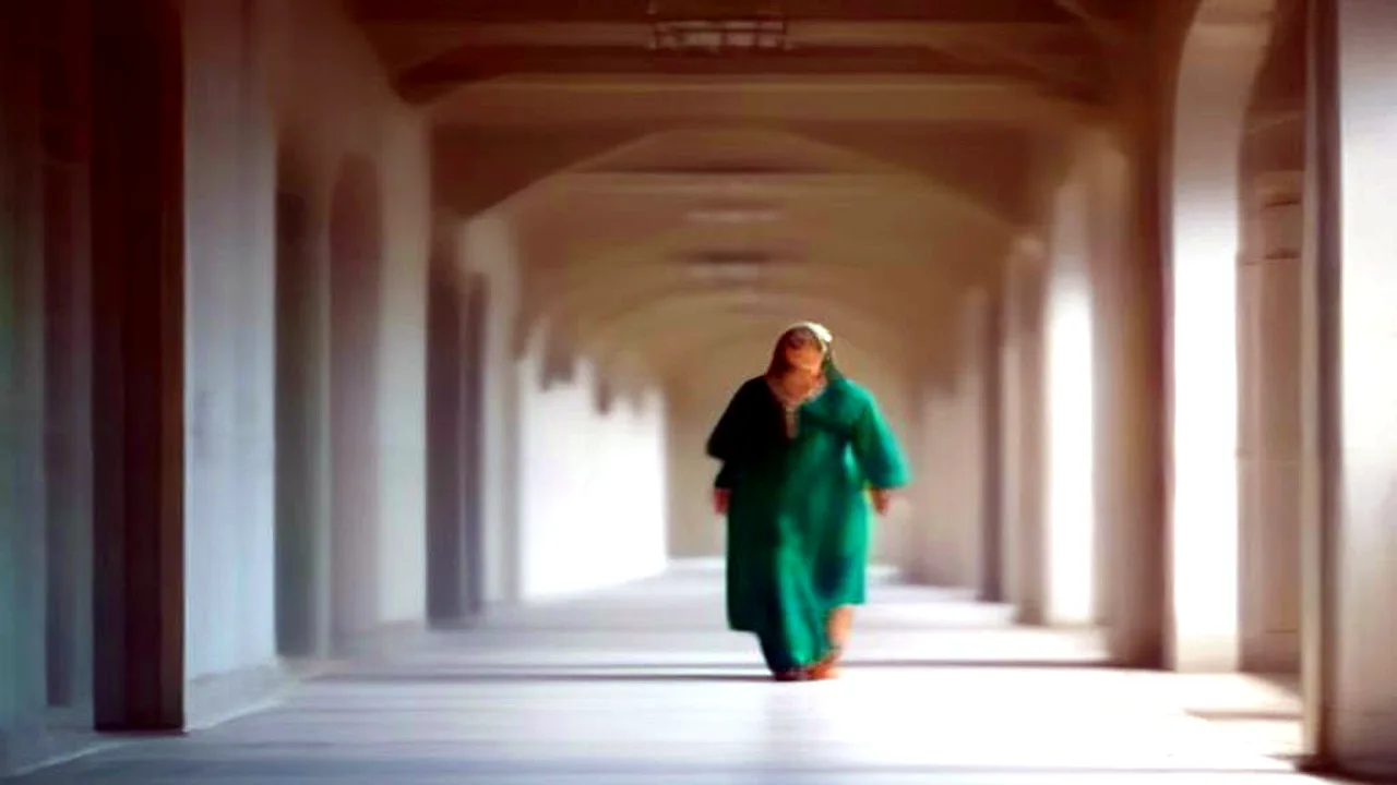 PM Laptop Scheme 2026: A female university student standing in a brightly lit campus hallway, discussing academic documents with a